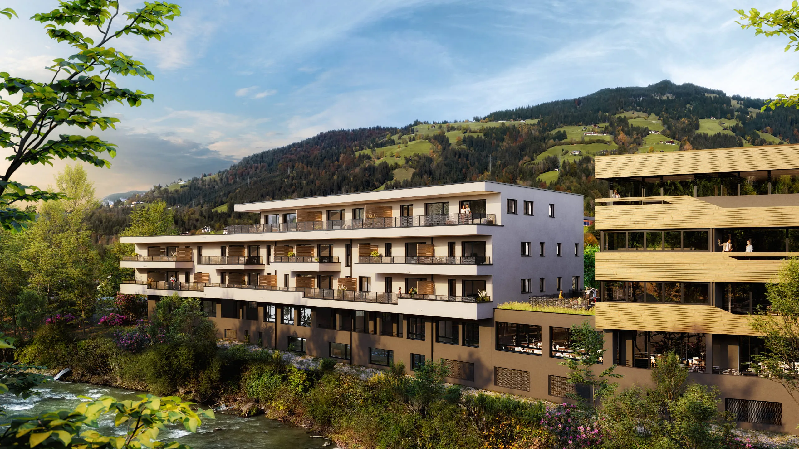 Moderne Wohnanlage von Pletzer Immobilien am Fluss, mit Bergpanorama im Hintergrund.